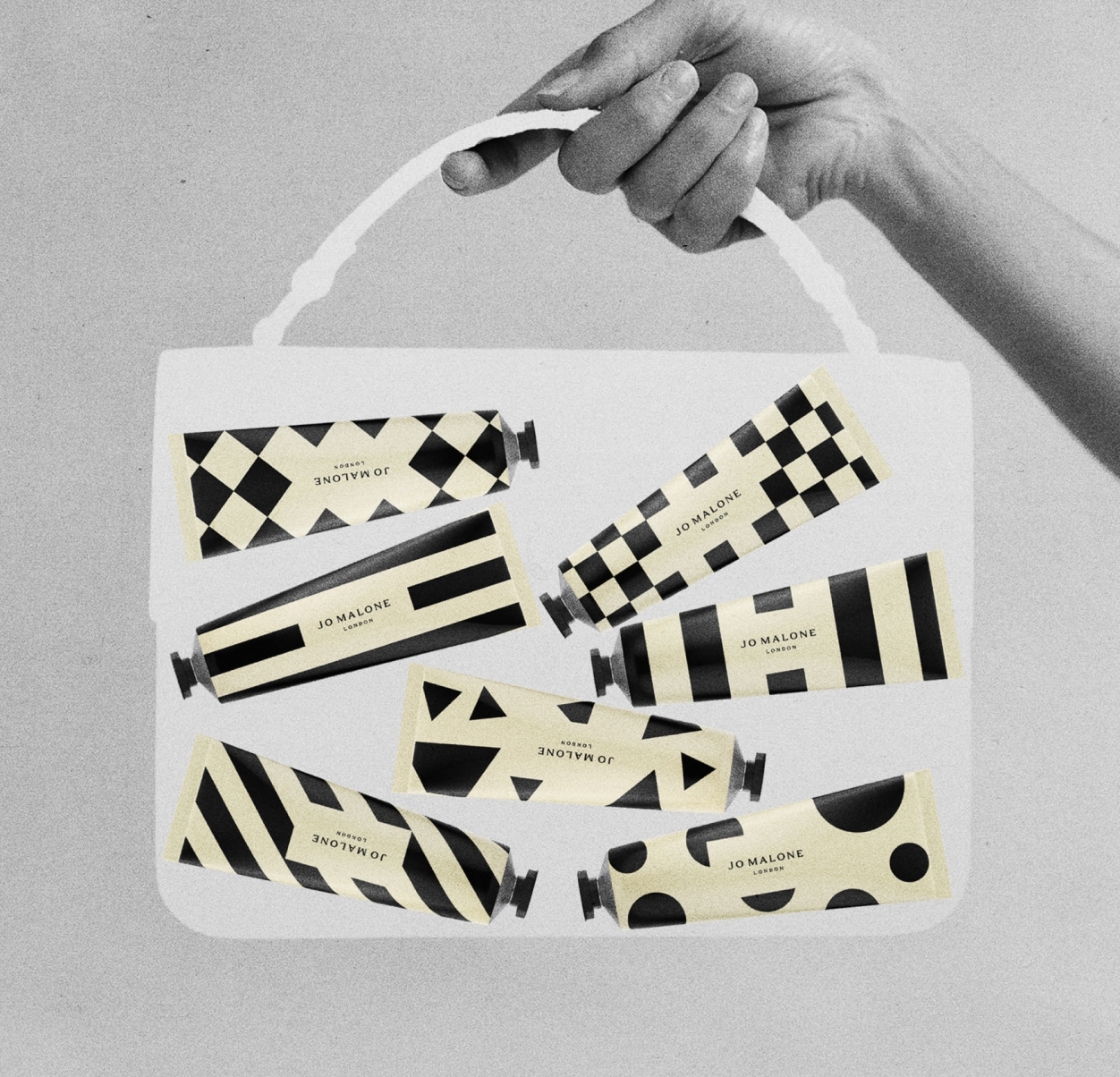 Immagine in bianco, nero e crema di una borsa media trasparente tenuta da una mano, contenente sette tubi di crema mani decorati.